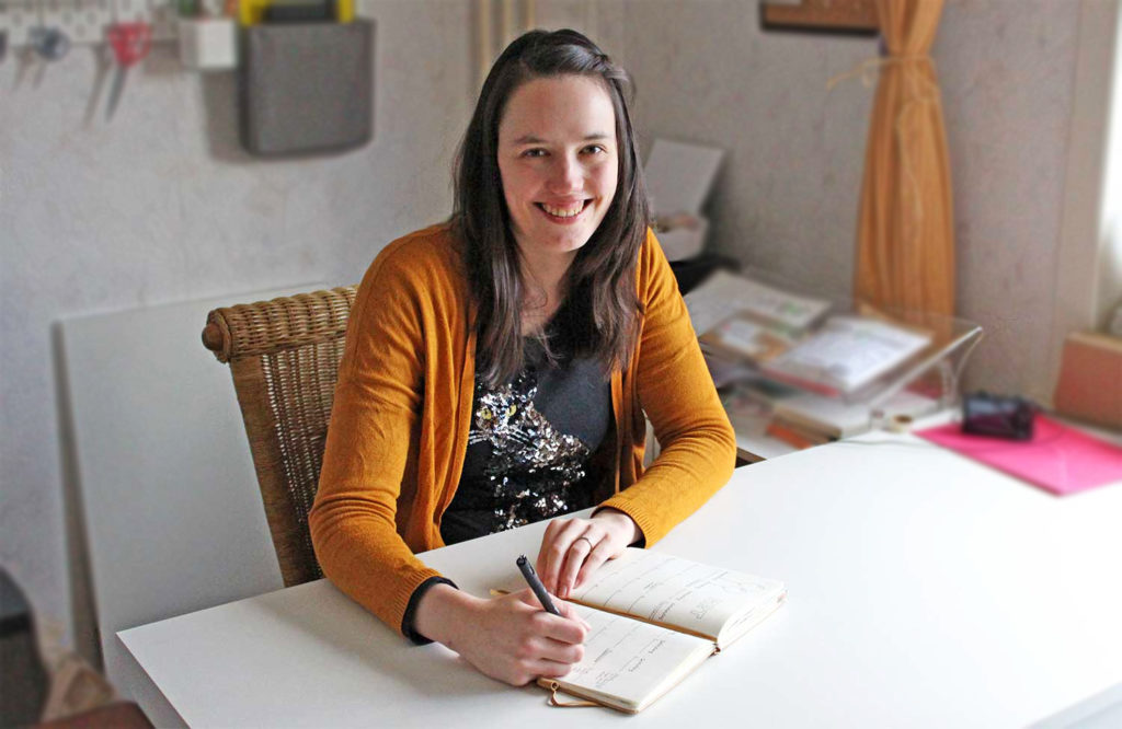 Anouk achter haar bureau met notitieboek en pen